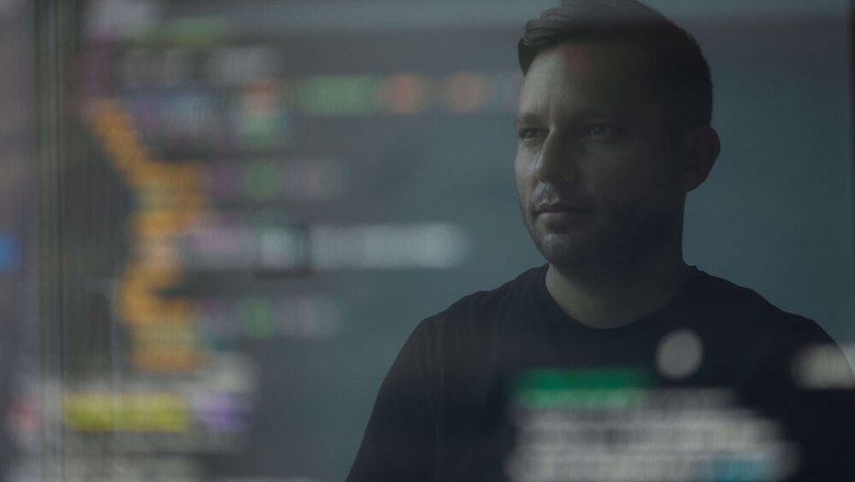 Человек, размышляющий о работе тимлида, в отражении экрана компьютера.